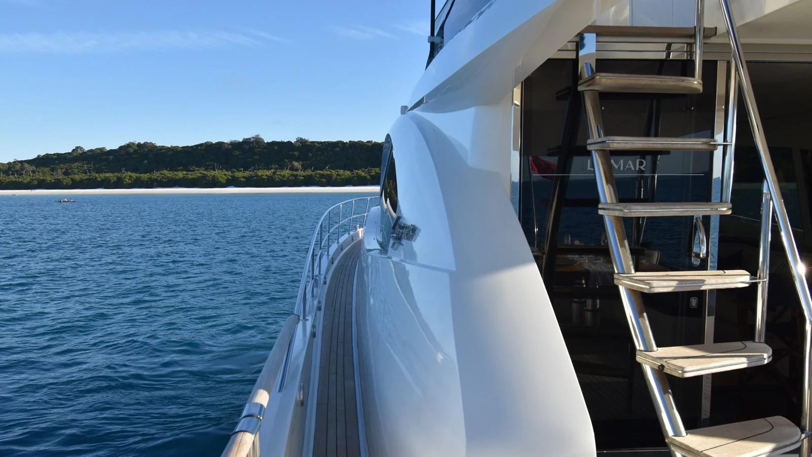 A sleek yacht is docked on calm waters with a view of the coastline in the background. aboard LA MAR Yacht for Sale