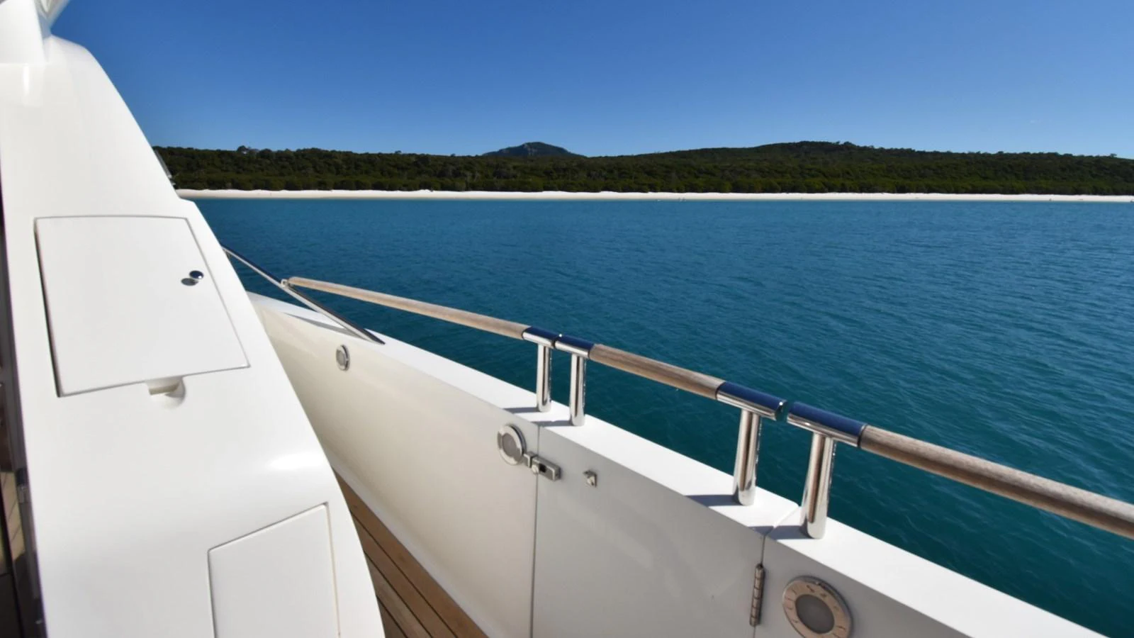 The yacht's sleek exterior is showcased against a backdrop of serene blue waters and a distant shoreline. aboard LA MAR Yacht for Sale