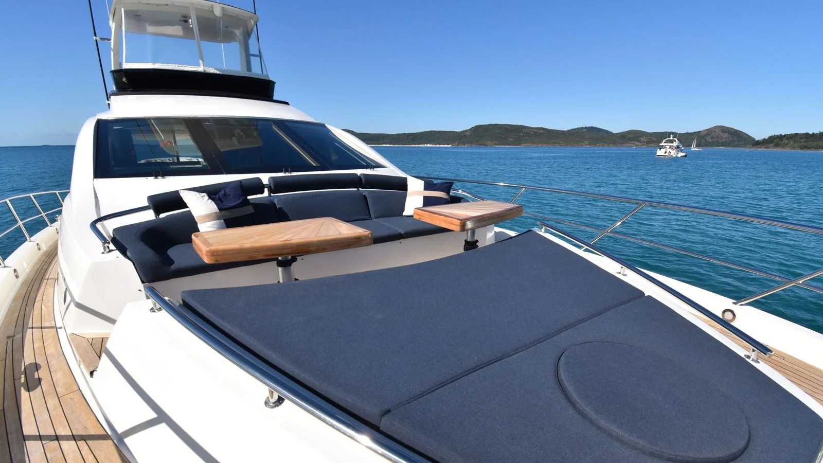 The yacht's bow area features a spacious sunpad with comfortable seating and wooden tables, perfect for relaxation under the sun. aboard LA MAR Yacht for Sale