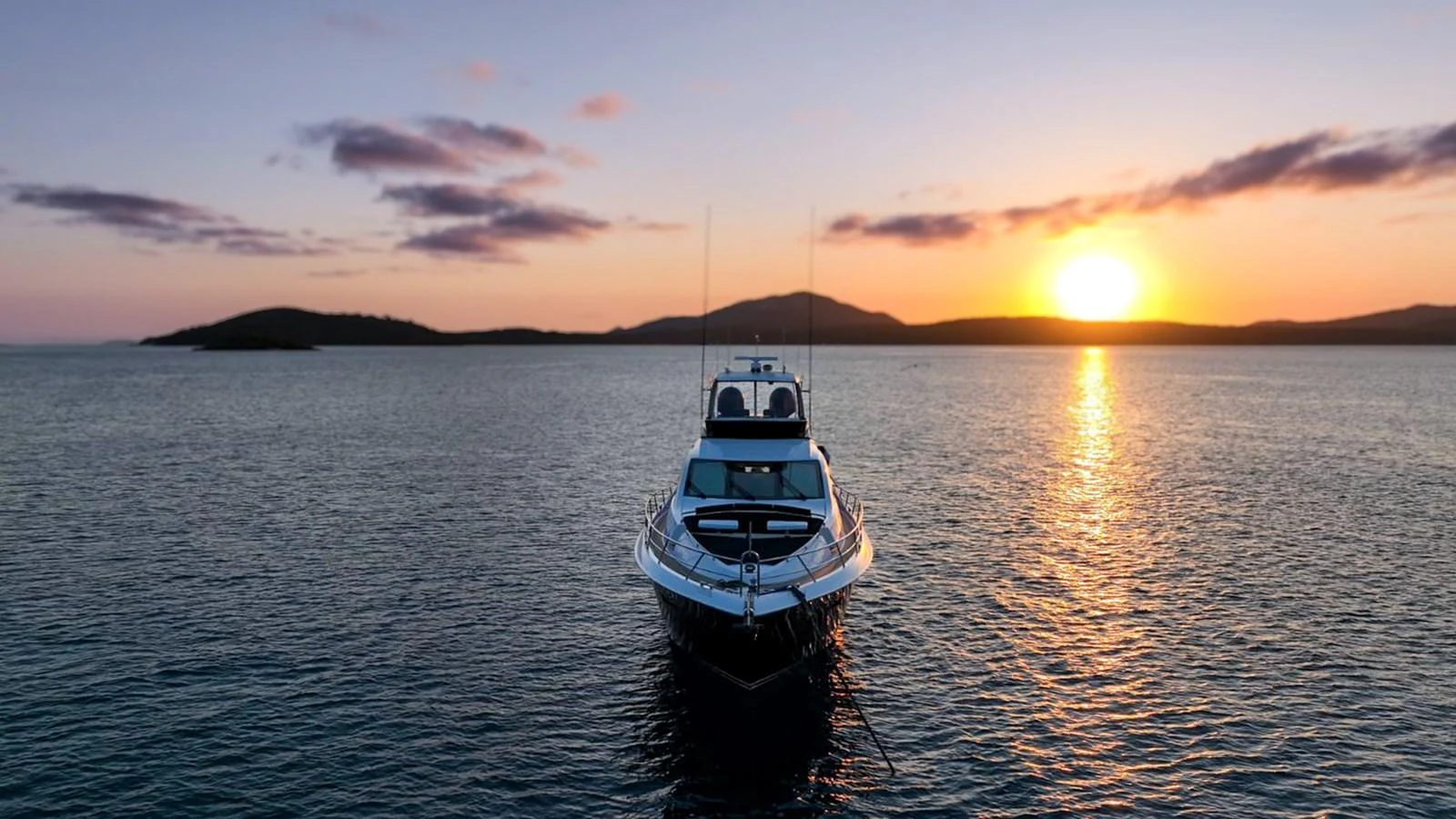 A yacht is anchored on calm waters at sunset, creating a serene and picturesque scene. aboard LA MAR Yacht for Sale