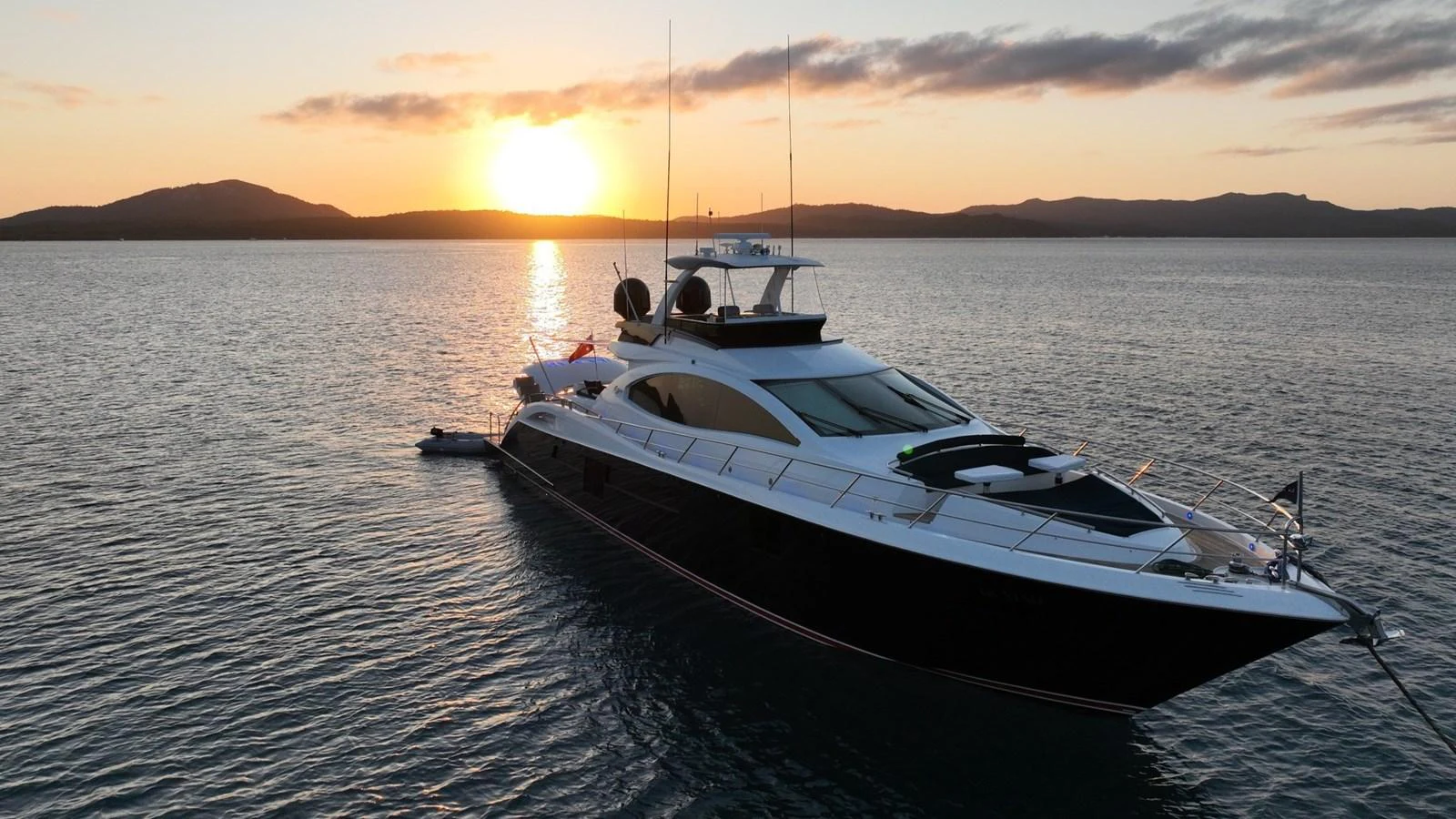 A sleek yacht is anchored on calm waters at sunset, showcasing its elegant design against a picturesque backdrop. aboard LA MAR Yacht for Sale