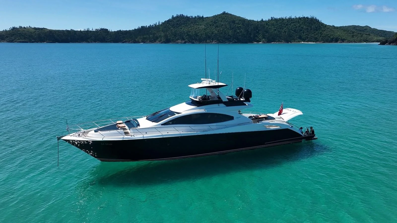 A sleek and modern yacht glides gracefully on turquoise waters with a scenic island backdrop. aboard LA MAR Yacht for Sale