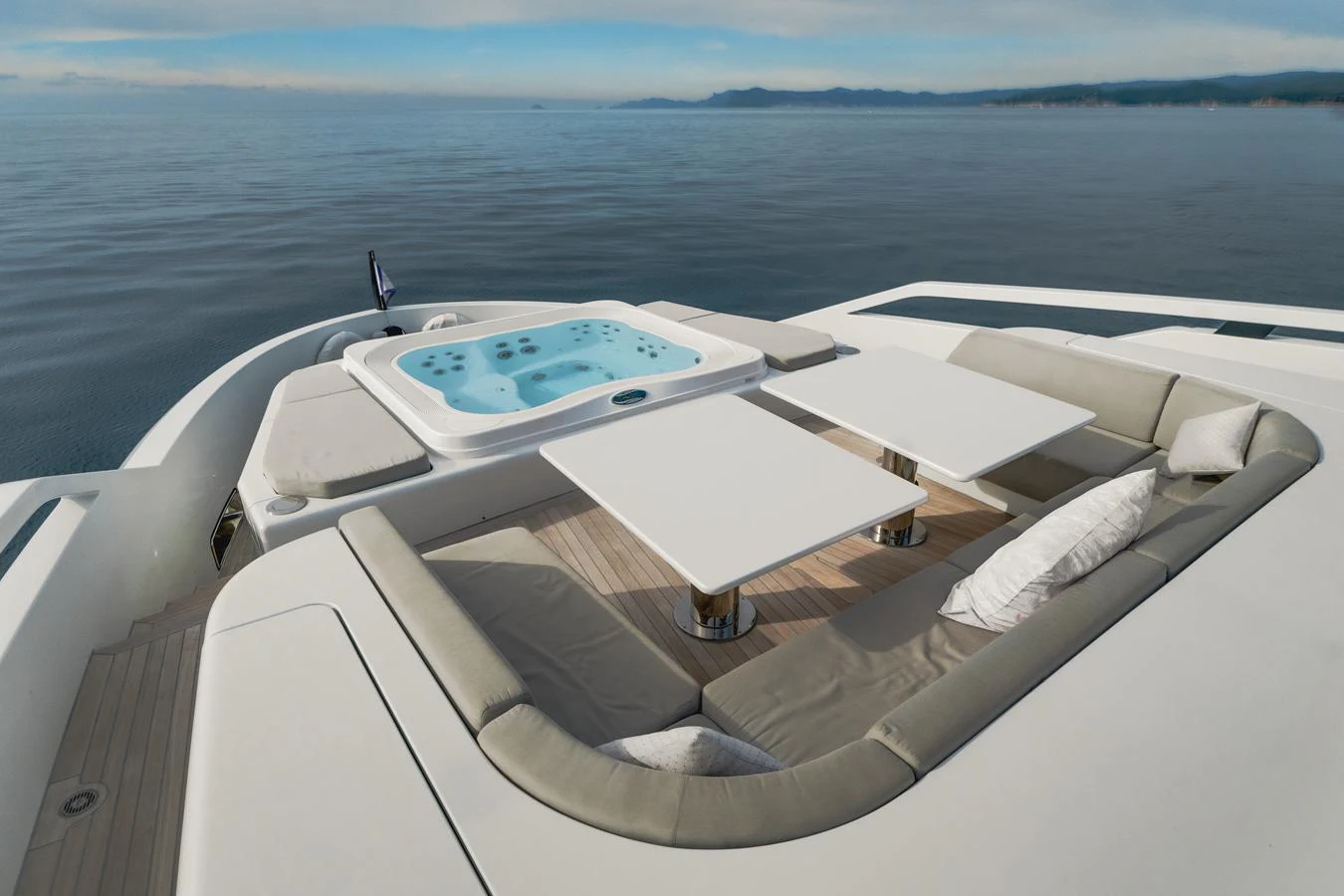 The sundeck features a luxurious jacuzzi surrounded by comfortable seating and tables, offering a perfect spot for relaxation with a stunning ocean view. aboard L.A.U.L. Yacht for Sale