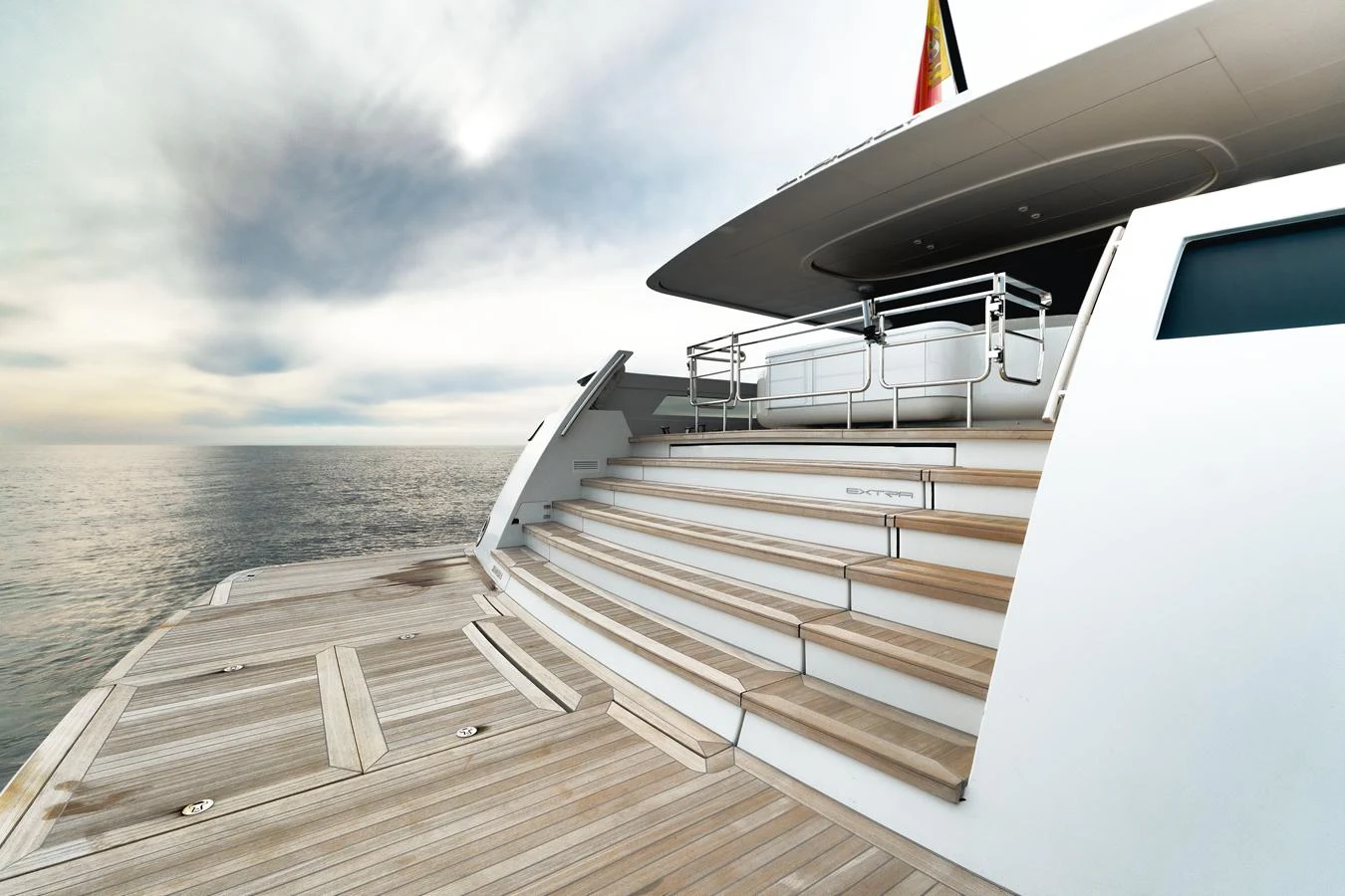The aft deck features elegant wooden steps leading up to a shaded seating area, overlooking the serene ocean. aboard L.A.U.L. Yacht for Sale