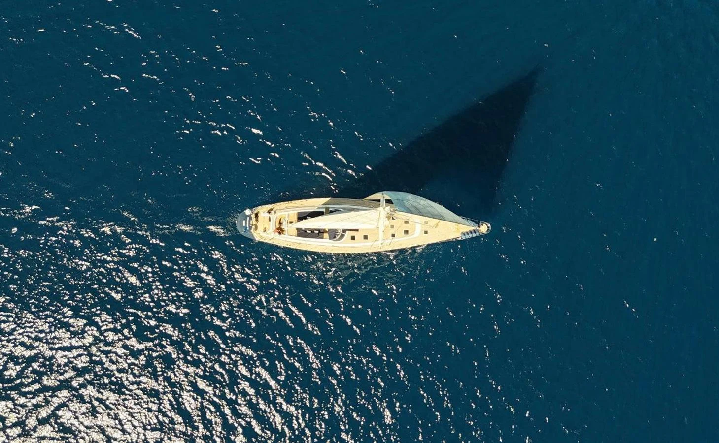 An aerial view of a sleek sailing yacht cutting through the deep blue sea. aboard PERSISTENCE Yacht for Sale