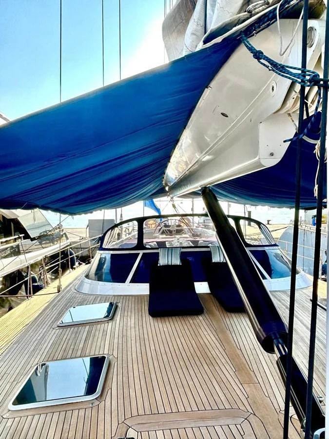 The yacht's deck features sleek wooden flooring and a shaded area for relaxation. aboard PERSISTENCE Yacht for Sale