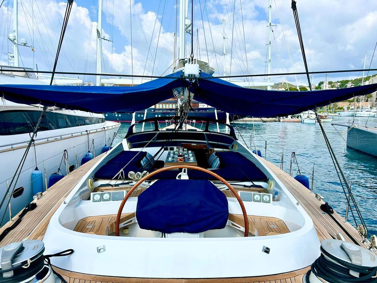 The aft deck of this yacht features a spacious and well-equipped helm station with a wooden steering wheel and blue covers. aboard PERSISTENCE Yacht for Sale