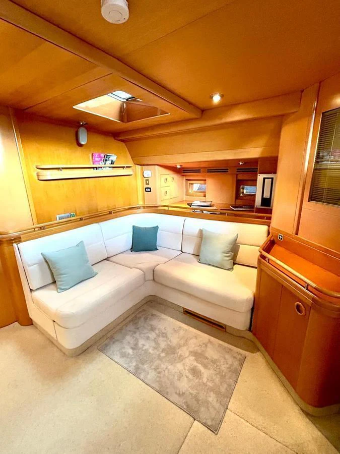 The yacht's salon features a cozy seating area with plush cushions and warm wood finishes. aboard PERSISTENCE Yacht for Sale