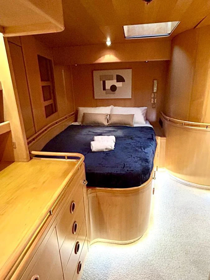 The stateroom features a cozy bed with elegant wood paneling and soft lighting. aboard PERSISTENCE Yacht for Sale