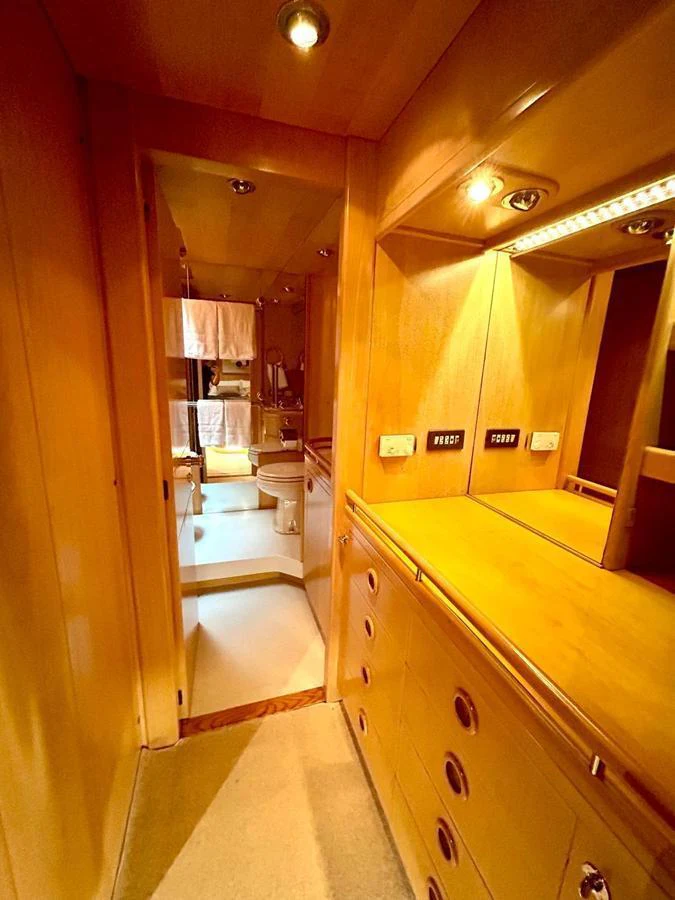A warm, wood-paneled hallway leading to a well-lit bathroom area. aboard PERSISTENCE Yacht for Sale