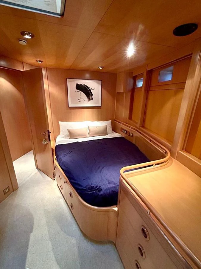 A cozy stateroom featuring a comfortable bed with a navy blue blanket and ample storage space. aboard PERSISTENCE Yacht for Sale