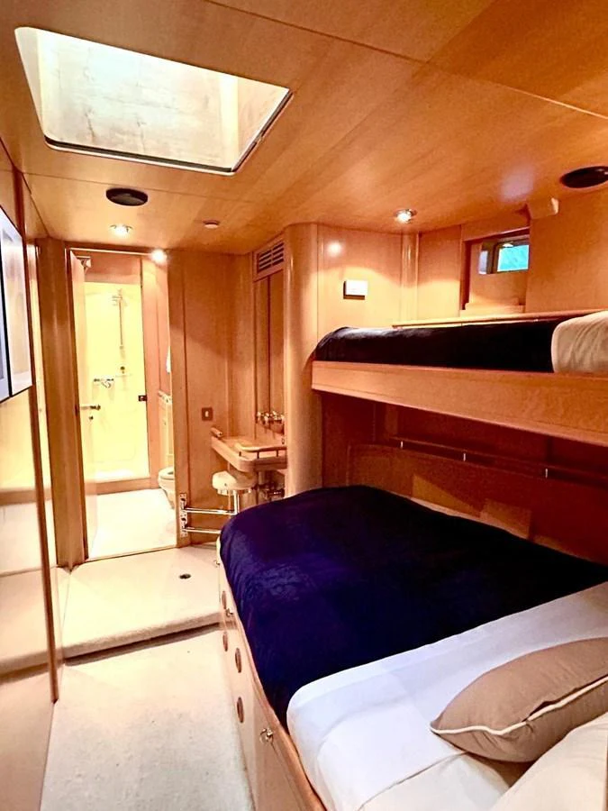 The cozy guest cabin features wooden paneling, a skylight, and comfortable bedding. aboard PERSISTENCE Yacht for Sale