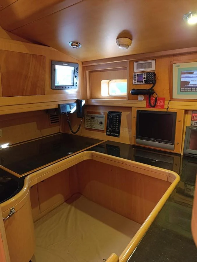 The helm station features advanced navigation equipment and a cozy, wood-paneled design. aboard PERSISTENCE Yacht for Sale