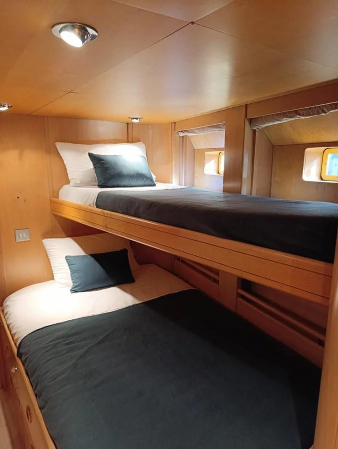 The cozy bunk cabin features comfortable bedding and warm wood paneling. aboard PERSISTENCE Yacht for Sale