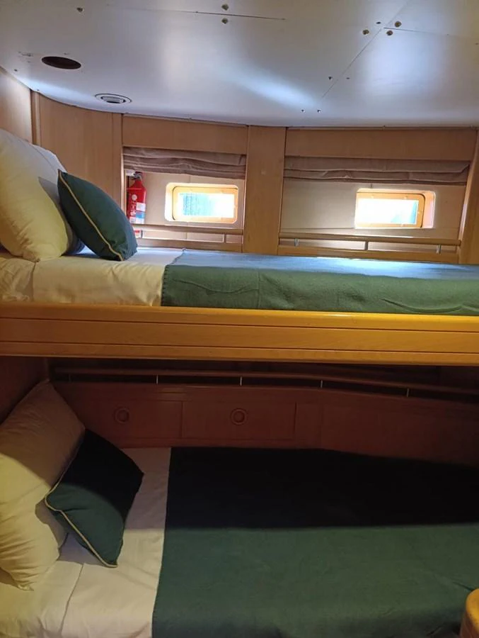 A cozy cabin with bunk beds and natural light from small windows. aboard PERSISTENCE Yacht for Sale