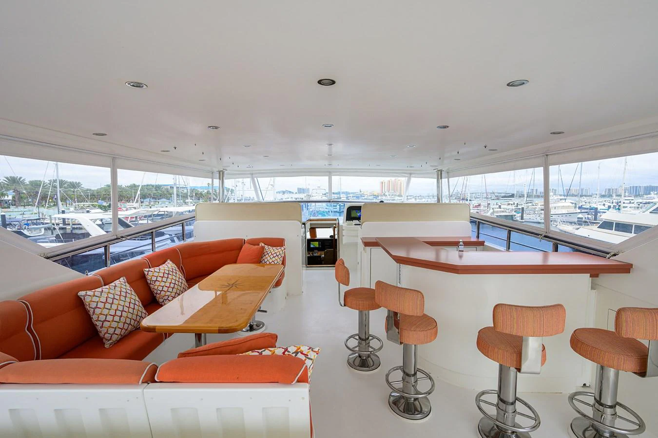 a room with orange couches and a table with chairs aboard DUNIA Yacht for Sale