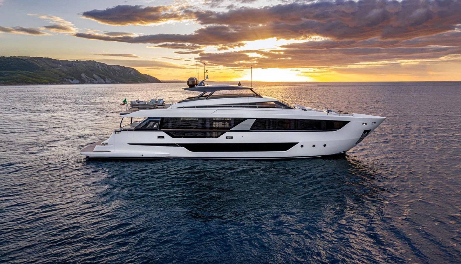A sleek and modern yacht glides through calm waters at sunset, showcasing its elegant design. aboard EPIC Yacht for Sale