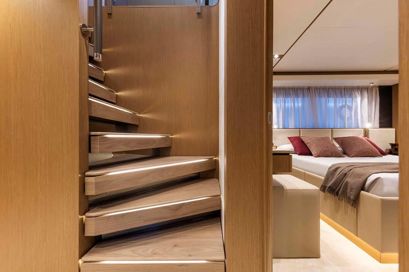 A luxurious interior featuring a modern staircase leading to a cozy stateroom with elegant furnishings. aboard EPIC Yacht for Sale