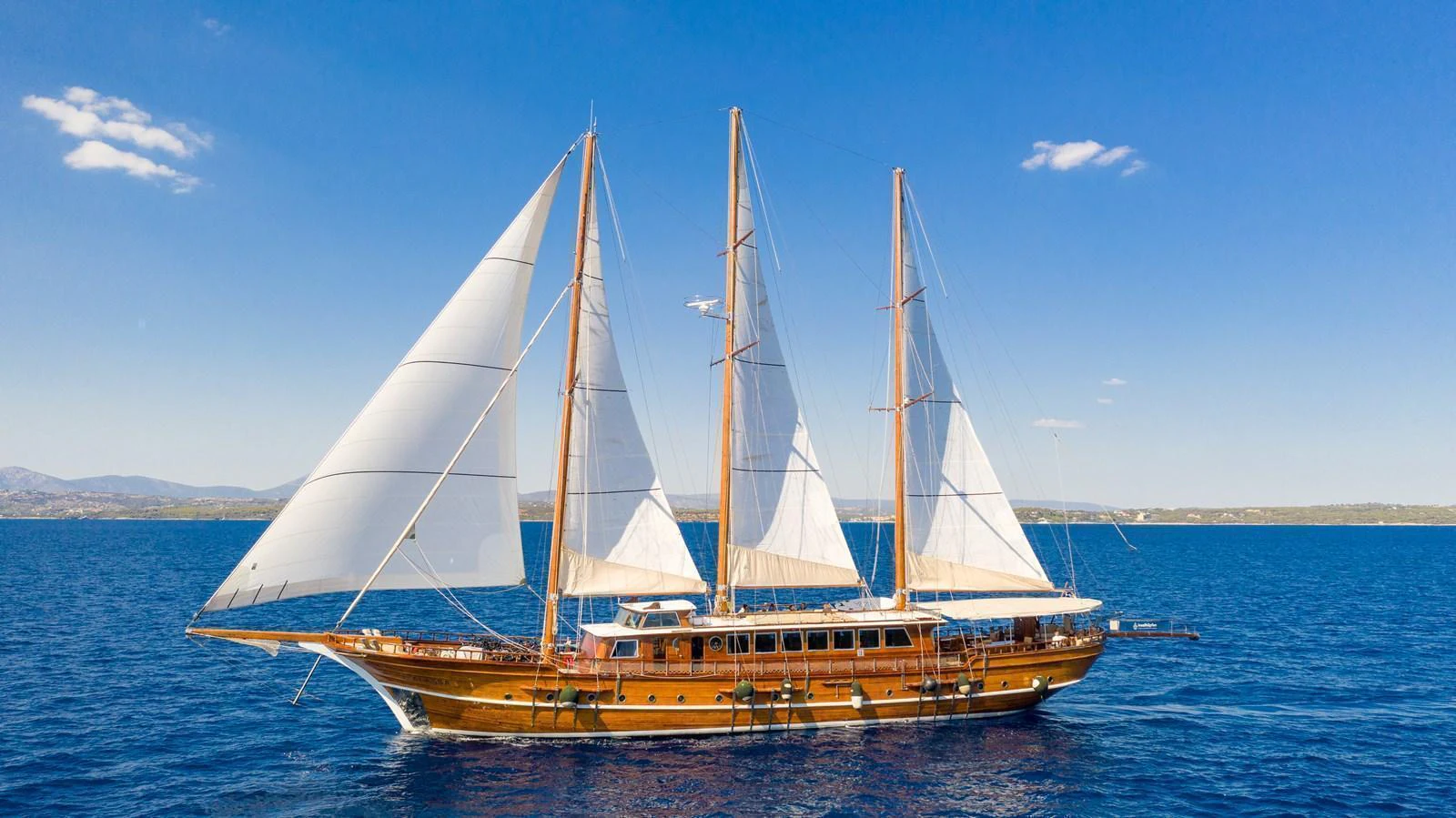 A stunning sailing yacht glides gracefully on the open sea under clear blue skies. aboard THALASSA Yacht for Sale