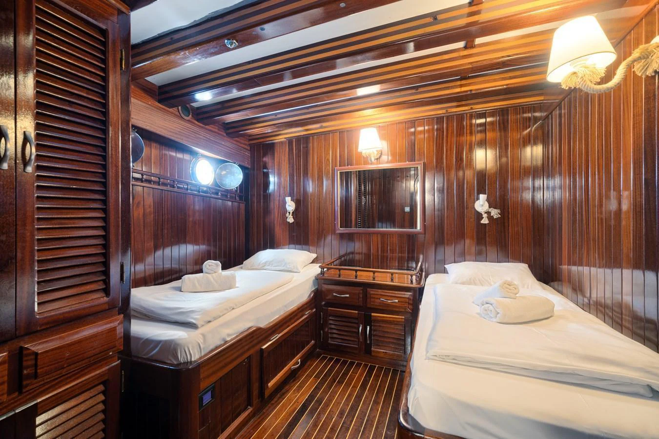 The guest cabin features twin beds with polished wood paneling and ambient lighting. aboard THALASSA Yacht for Sale