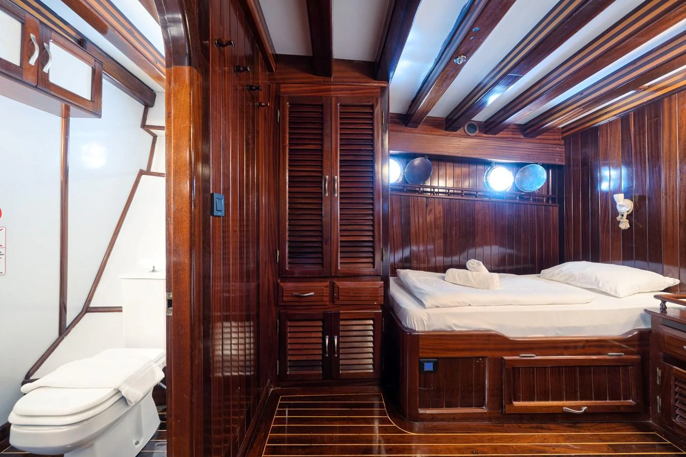 The stateroom features rich wood paneling and a cozy bed, creating a warm and inviting atmosphere. aboard THALASSA Yacht for Sale