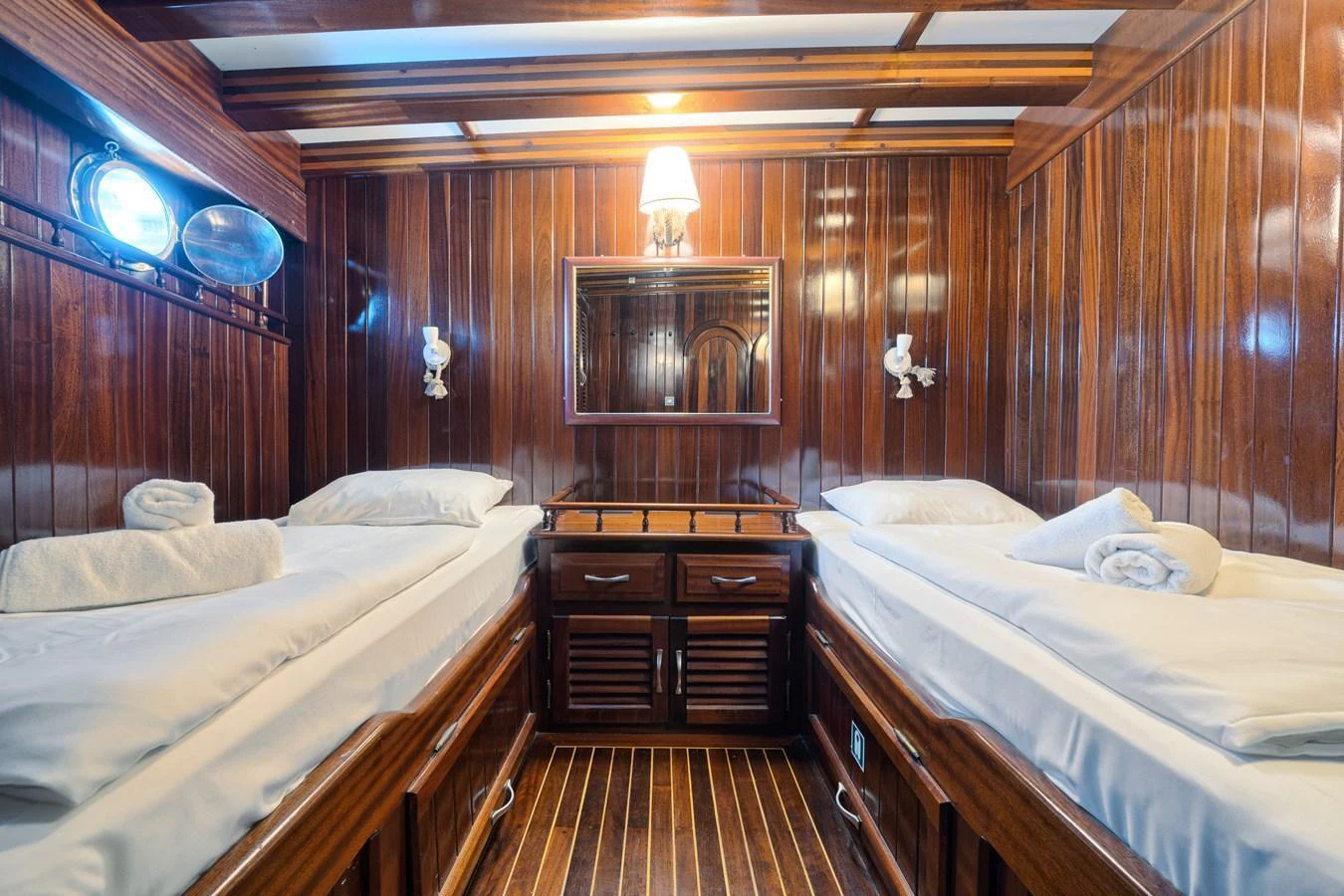 The twin cabin features rich wooden paneling and cozy twin beds with elegant lighting. aboard THALASSA Yacht for Sale