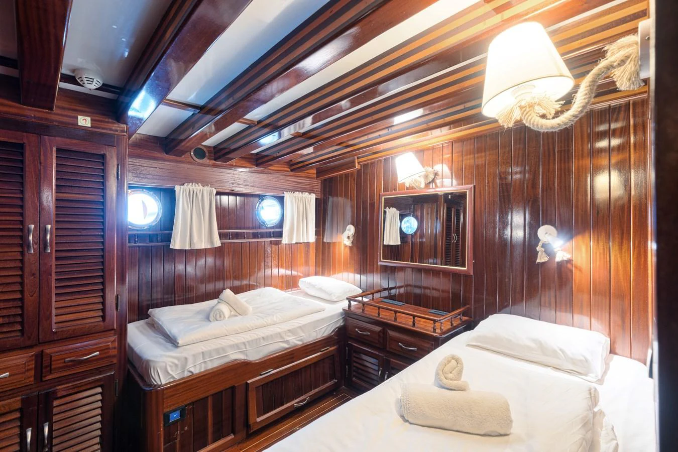 The guest cabin features twin beds with elegant wooden paneling and soft lighting. aboard THALASSA Yacht for Sale