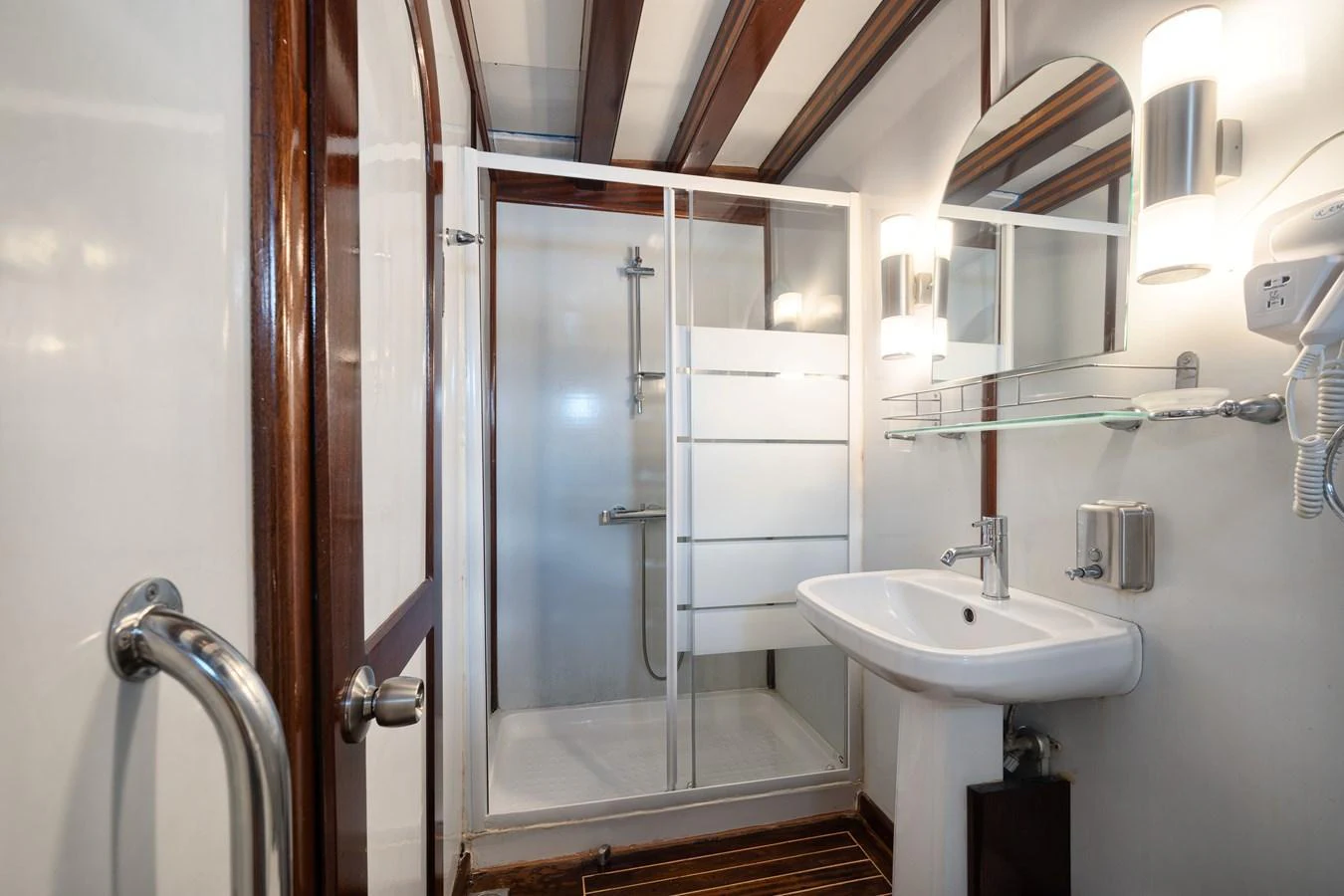 The yacht's bathroom features a modern shower, sink, and elegant wood accents. aboard THALASSA Yacht for Sale