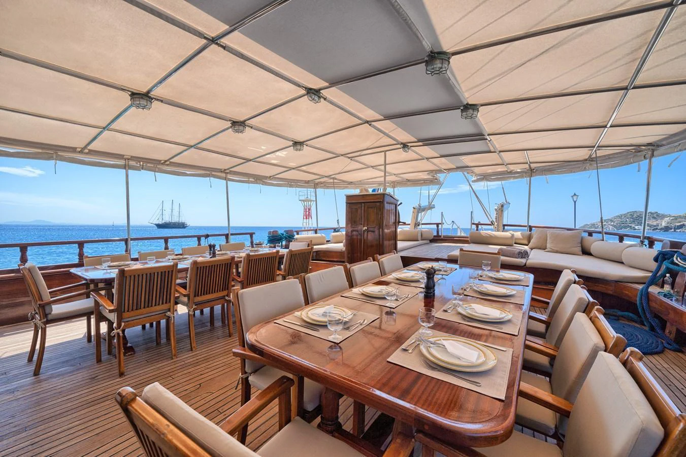 The spacious aft deck features elegant dining and lounging areas under a shaded canopy. aboard THALASSA Yacht for Sale