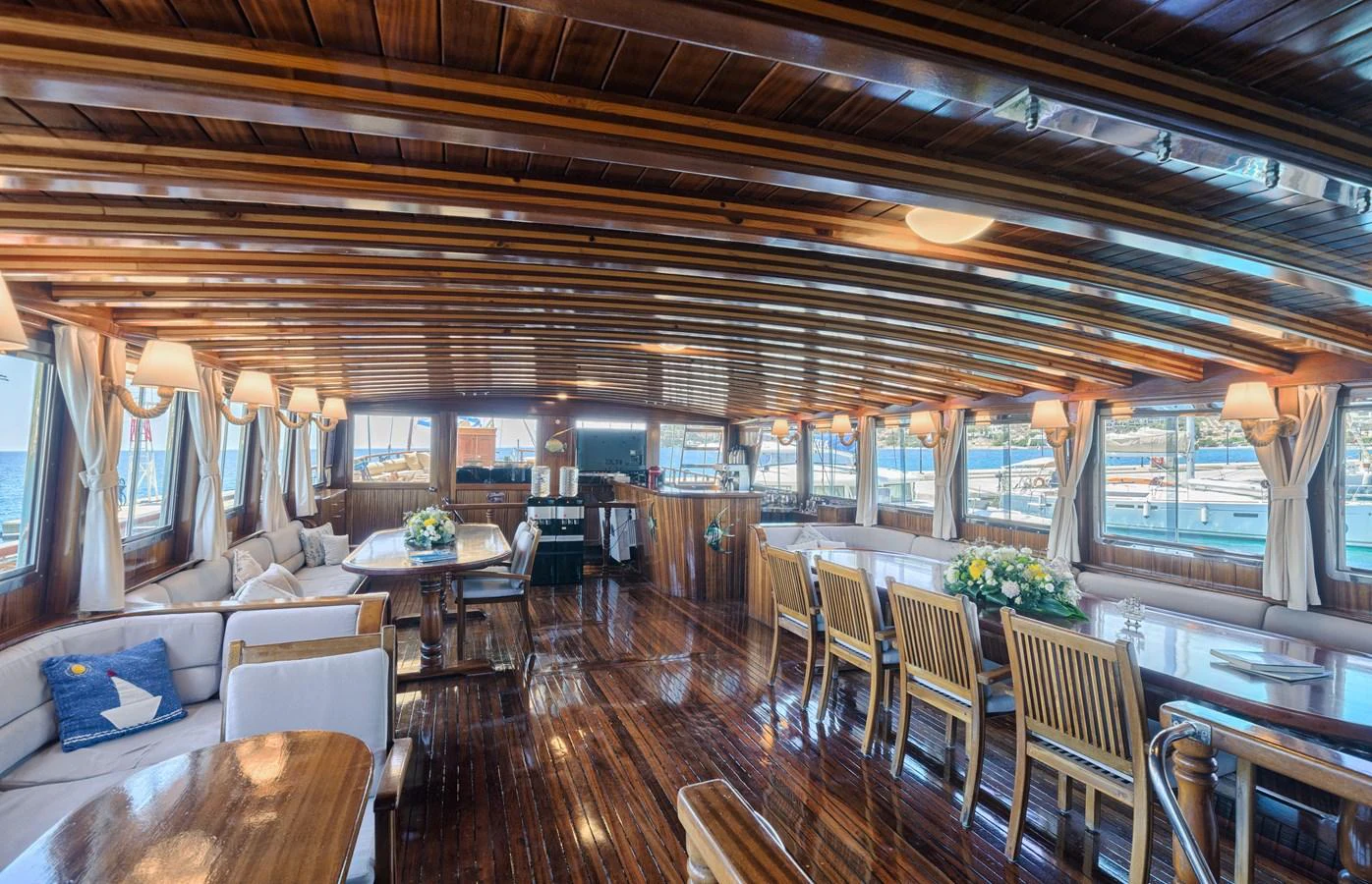 The yacht's salon features elegant wooden finishes and ample seating with large windows providing stunning views. aboard THALASSA Yacht for Sale