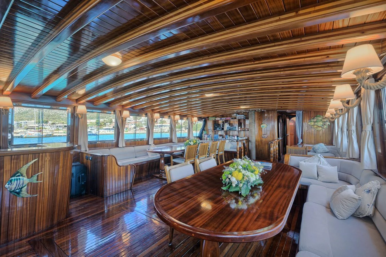 The yacht's salon features luxurious wooden finishes and ample seating with a large dining table. aboard THALASSA Yacht for Sale