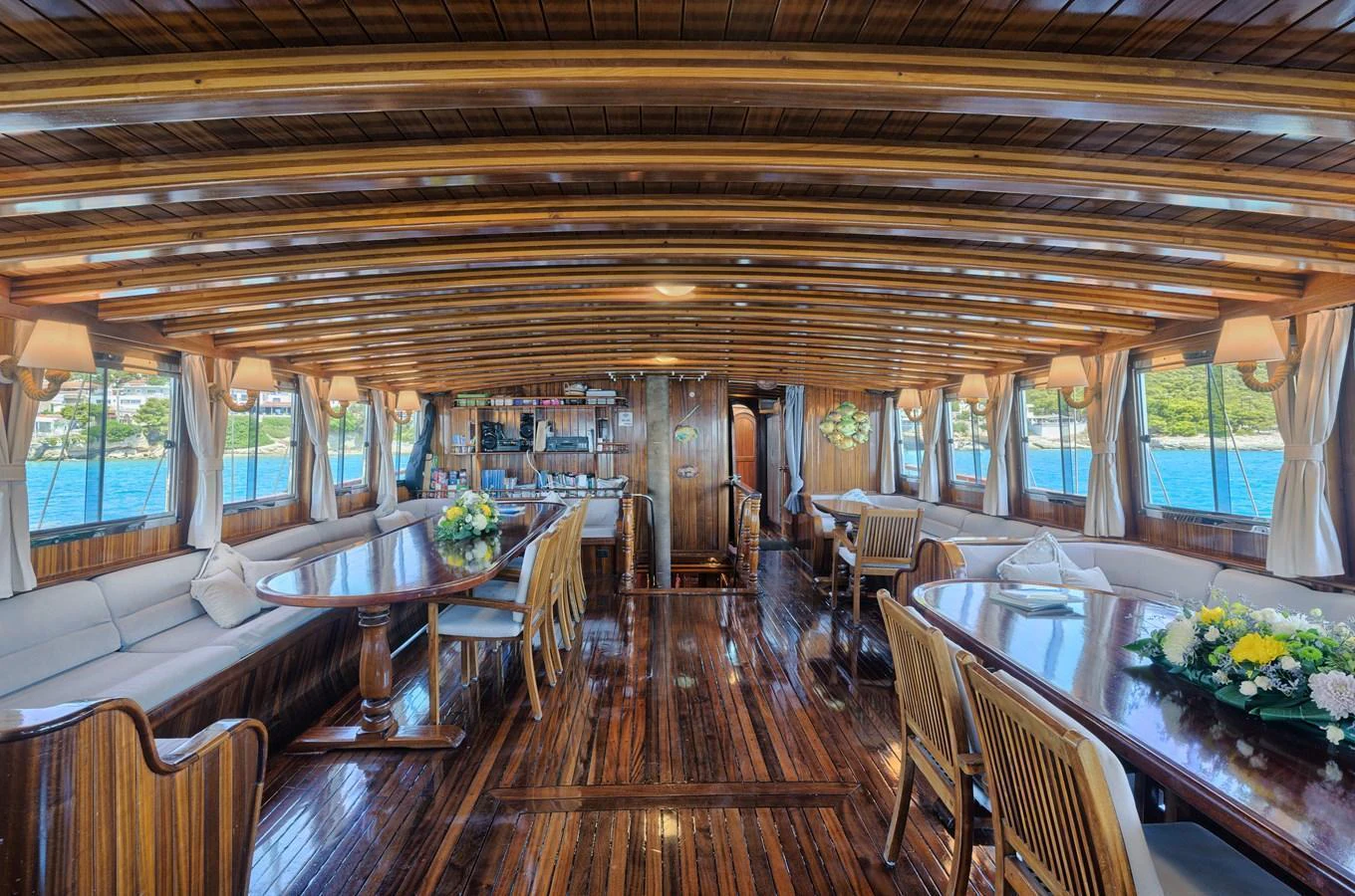 The yacht's salon features elegant wooden interiors with ample seating and panoramic windows. aboard THALASSA Yacht for Sale