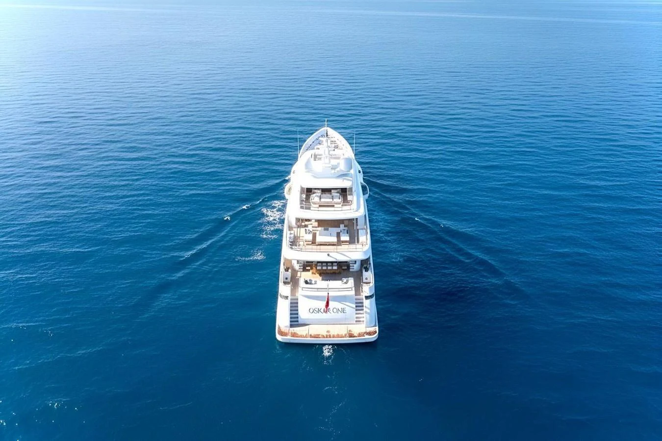A luxurious yacht cruising on calm, clear blue waters, showcasing its elegant design from the rear. aboard OSKAR ONE Yacht for Sale