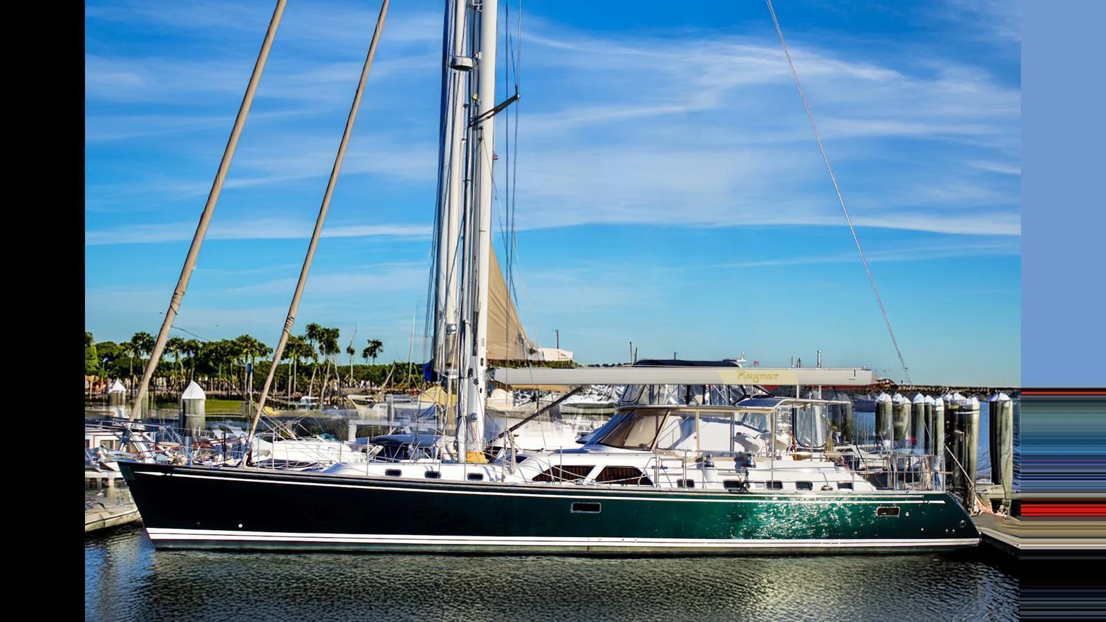 A sleek sailing yacht is docked at a marina under a clear blue sky. aboard RAGNAR Yacht for Sale