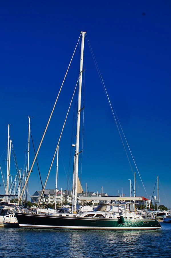 A sleek yacht with tall masts is docked at a marina under a clear blue sky. aboard RAGNAR Yacht for Sale