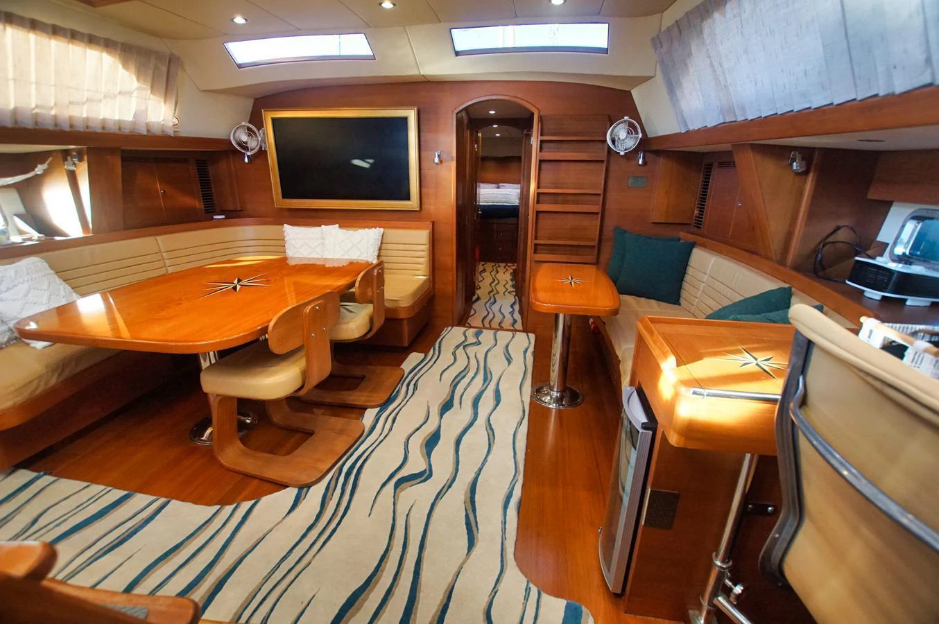 The salon features elegant wood finishes, a comfortable seating area, and a modern entertainment system. aboard RAGNAR Yacht for Sale