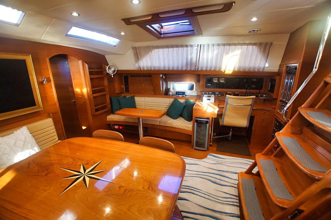 The yacht's saloon features a cozy dining area with a wooden table and comfortable seating, complemented by natural light from overhead windows. aboard RAGNAR Yacht for Sale