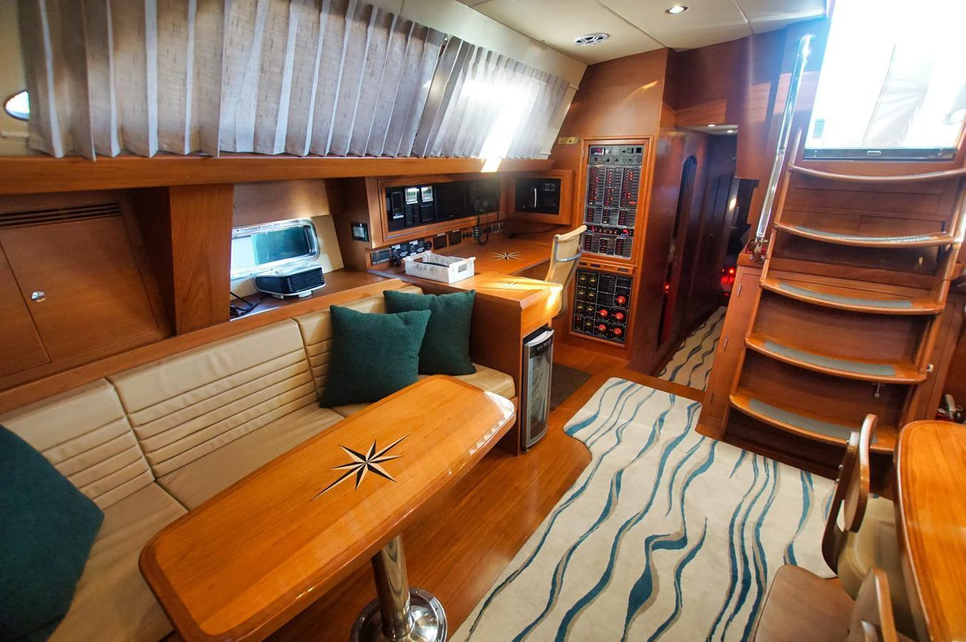 The yacht's salon features a cozy seating area with a stylish wooden table and modern amenities. aboard RAGNAR Yacht for Sale