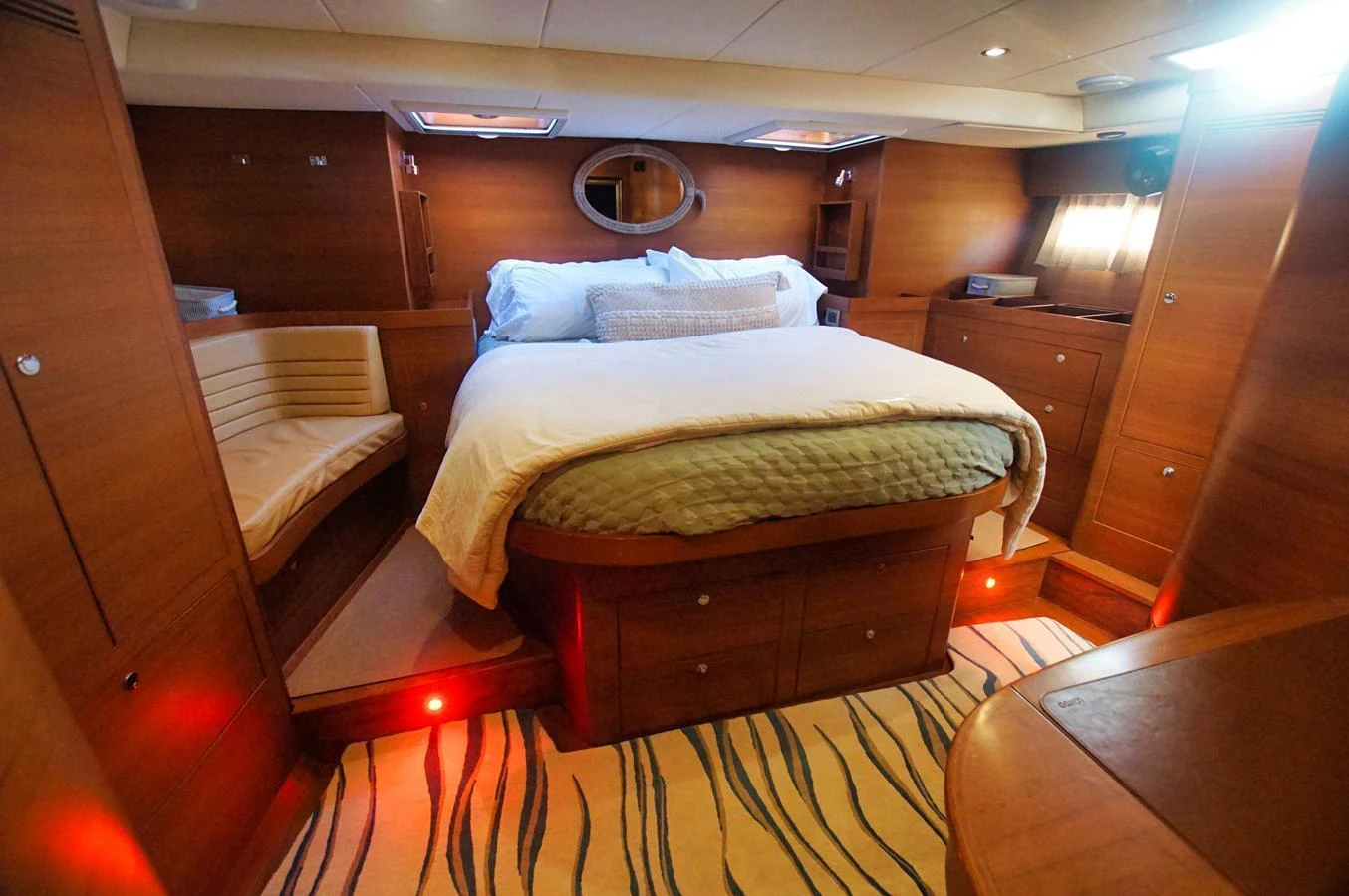 The stateroom features a cozy bed with warm wooden finishes and ambient lighting. aboard RAGNAR Yacht for Sale