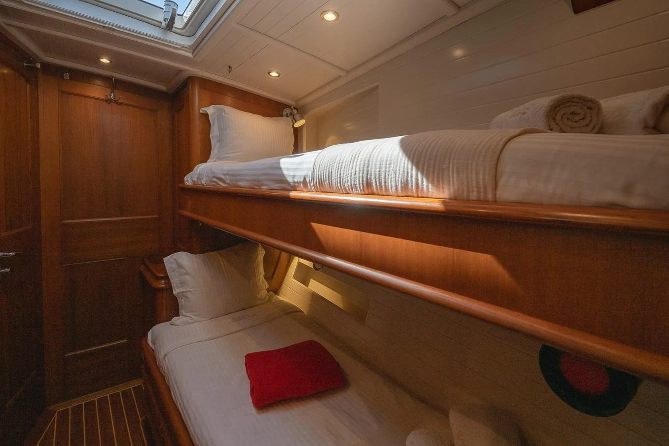 The cozy cabin features two neatly arranged bunk beds with warm wooden accents and soft lighting. aboard TEMPEST Yacht for Sale