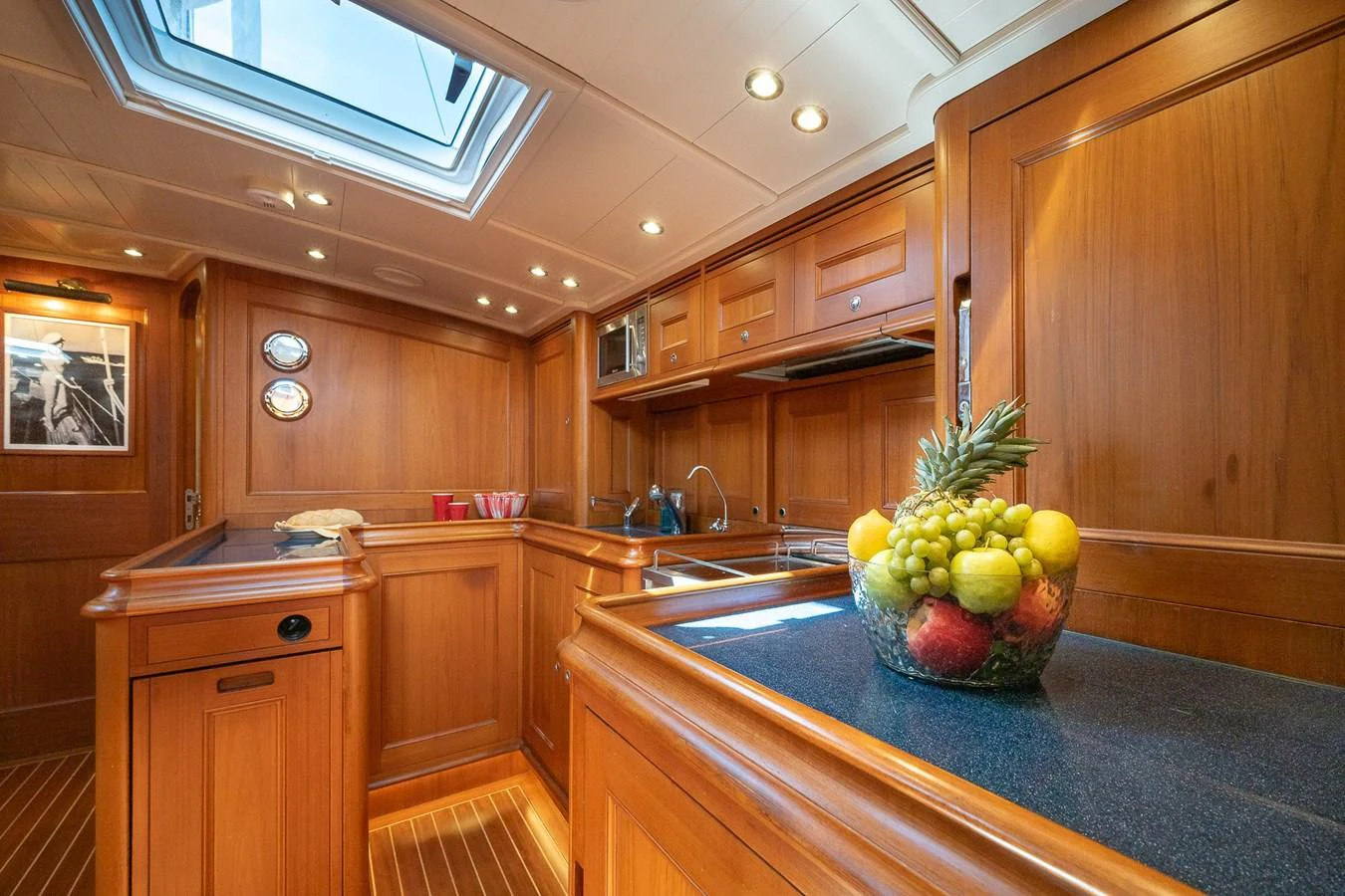 The yacht's galley features warm wooden cabinetry and modern amenities, creating a cozy and functional space. aboard TEMPEST Yacht for Sale