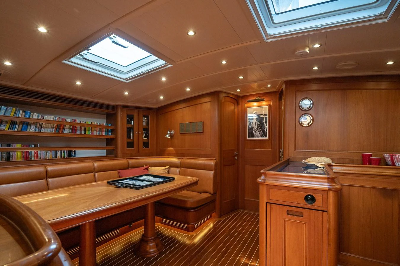 The yacht's saloon features elegant wood paneling, a comfortable seating area, and ample natural light from overhead skylights. aboard TEMPEST Yacht for Sale