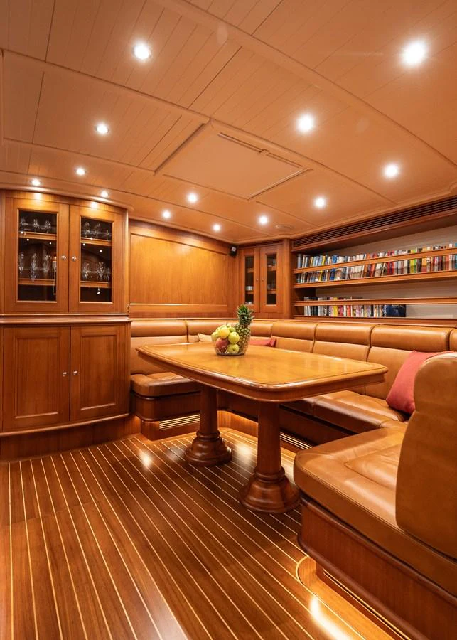 The yacht's dining area features elegant wood paneling, plush seating, and a well-lit ambiance. aboard TEMPEST Yacht for Sale
