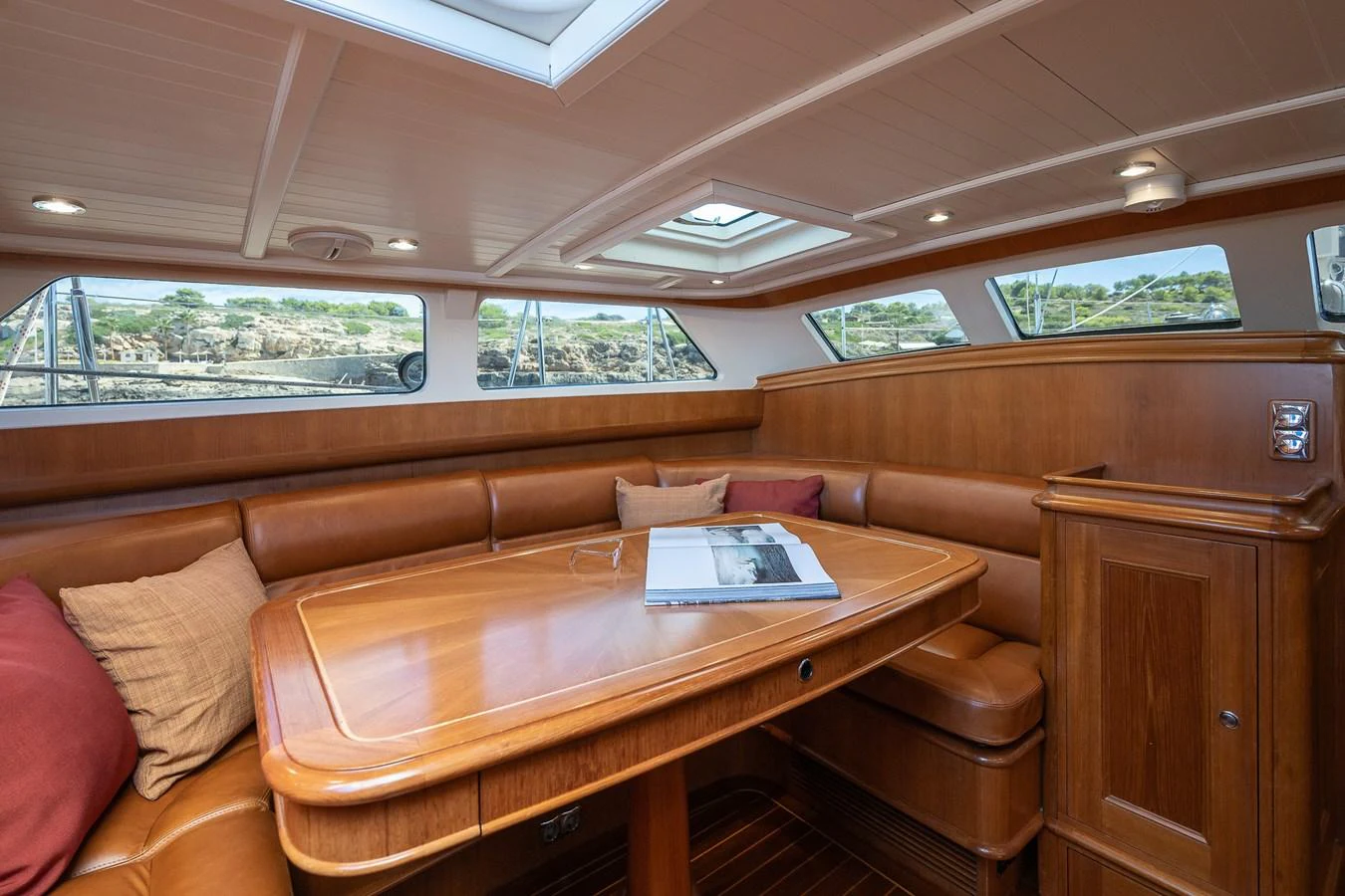 The saloon features a cozy seating area with a polished wooden table and ample natural light from the surrounding windows. aboard TEMPEST Yacht for Sale