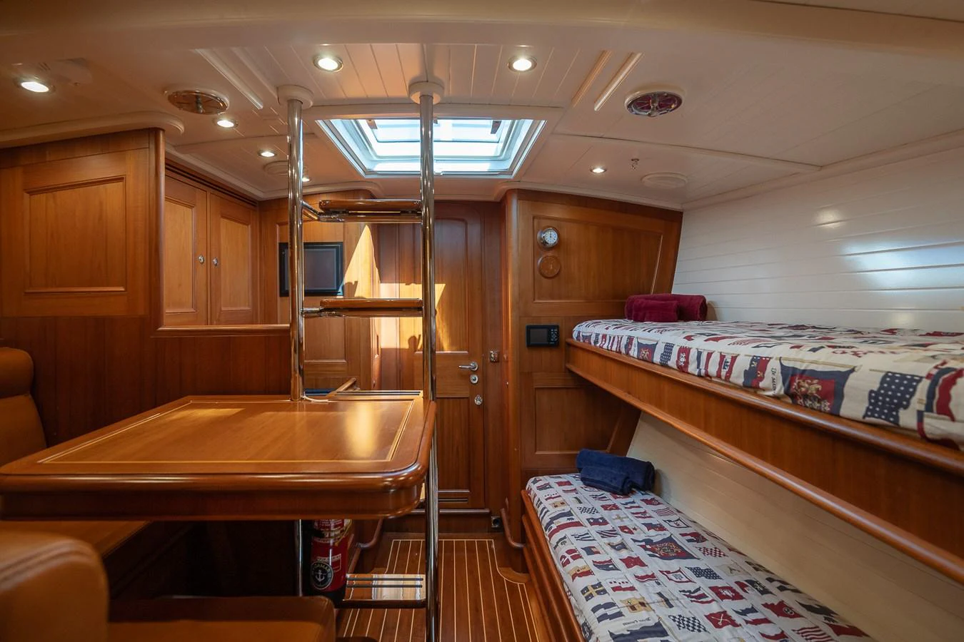The cozy cabin features wooden furnishings, bunk beds, and a skylight for natural light. aboard TEMPEST Yacht for Sale