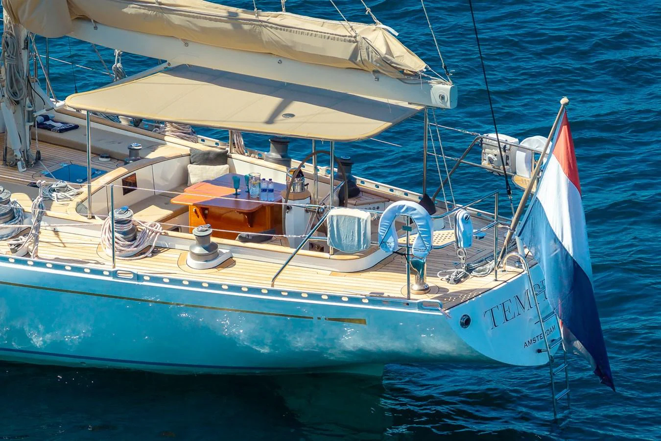 The aft deck of this elegant yacht features a shaded seating area and a beautifully varnished table, perfect for alfresco dining. aboard TEMPEST Yacht for Sale