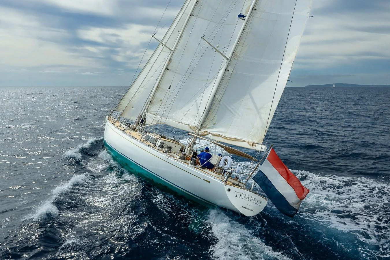 A classic sailing yacht gracefully cuts through the open sea under full sail. aboard TEMPEST Yacht for Sale