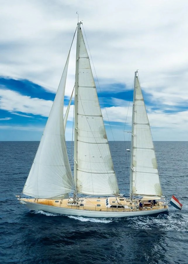 A stunning sailing yacht glides gracefully across the open sea under a clear blue sky. aboard TEMPEST Yacht for Sale