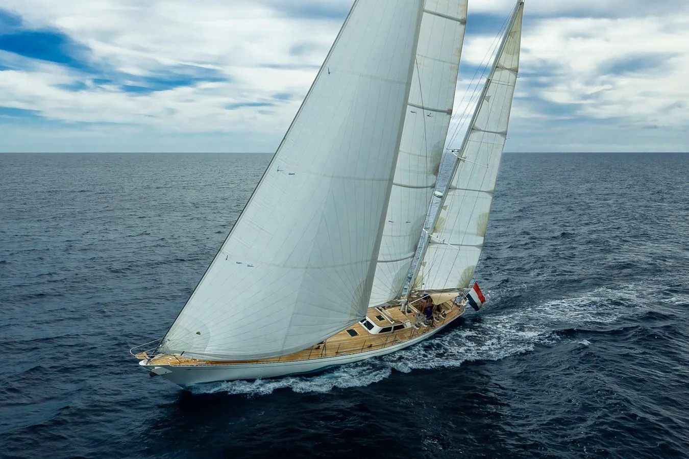 A stunning sailing yacht glides gracefully over the open sea under full sail. aboard TEMPEST Yacht for Sale