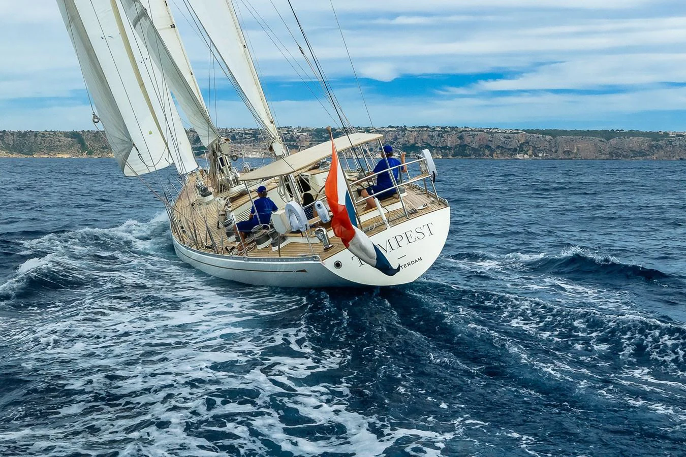 A sleek sailing yacht glides through the open sea with its sails fully extended. aboard TEMPEST Yacht for Sale